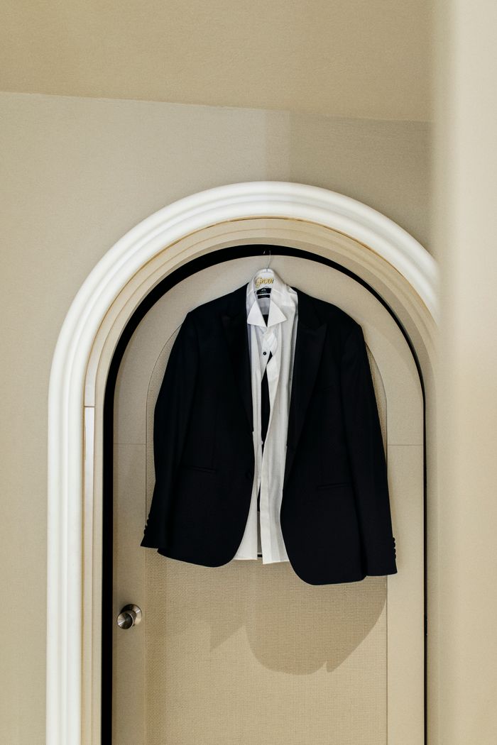 Crafting Captivating Headlines: Your awesome post title goes here Classic black suit and white shirt hanging on an arched door, showcasing elegance and sophistication.