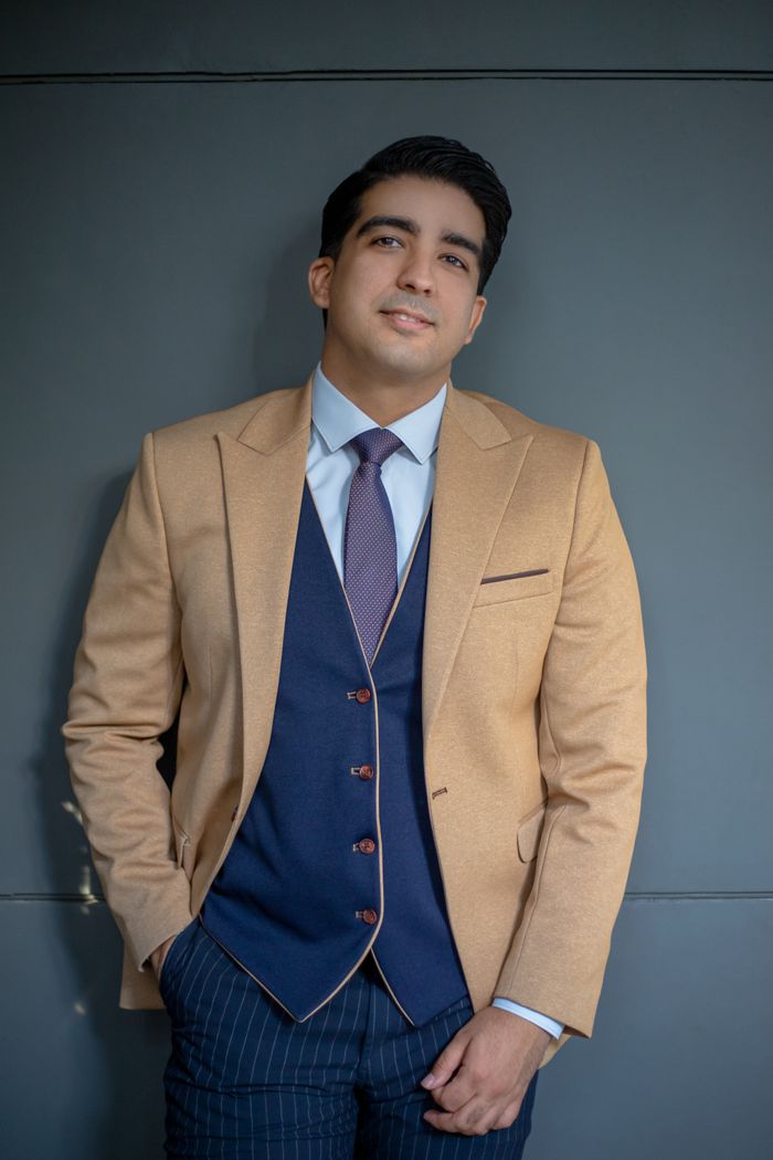 Mastering the First Impression: Your intriguing post title goes here A portrait of a confident man in a beige suit and blue tie, exuding sophistication.